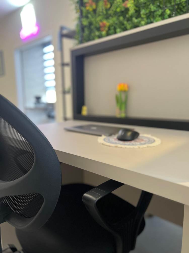 A desk by the green wall under the neon sign